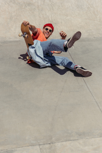 веселий чоловік в сонцезахисних окулярах падає зі скейтборду
 - Фото, зображення