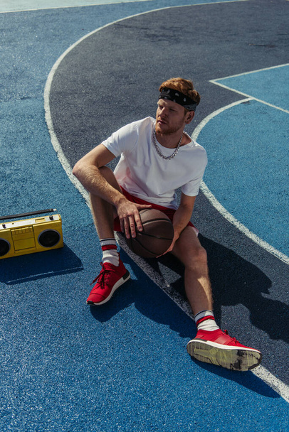 high angle view of sportsman in bandana sitting on court near boombox - Foto, afbeelding