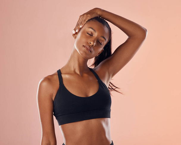 Slim, fit and stretching exercise of a woman feeling confident about her body and health against a pink studio background. Sporty and active woman staying healthy and in shape during a workout. - Foto, imagen