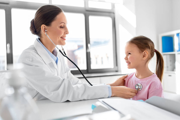 medicína, zdravotní péče a pediatrie - lékařka nebo pediatrička se stetoskopem a pacientka na lékařské prohlídce na klinice - Fotografie, Obrázek