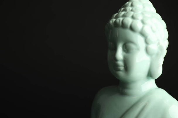 Beautiful ceramic Buddha sculpture on black background. Space for text - Фото, зображення