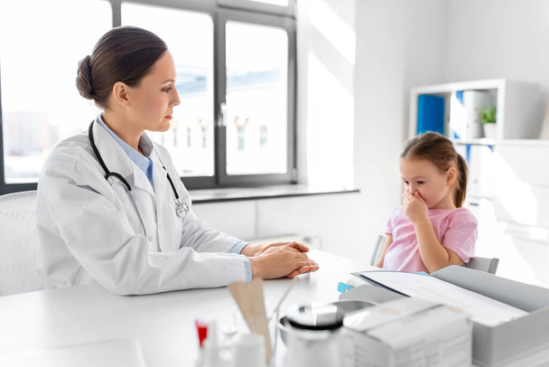 medicine, healthcare and pediatry concept - female doctor or pediatrician and coughing little girl patient on medical exam at clinic - Fotografie, Obrázek