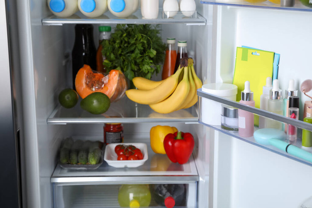 Storage of cosmetics in refrigerator door bin next to groceries - Foto, afbeelding