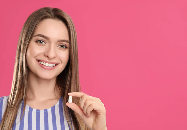Young woman with vitamin pill on pink background. Space for text - Фото, зображення
