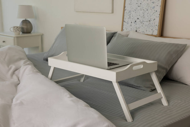 White tray table with laptop on bed indoors - Foto, Imagen