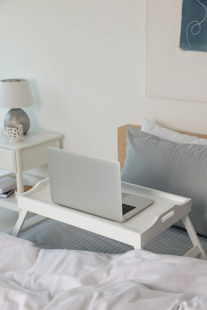 White tray table with laptop on bed indoors - Foto, Bild