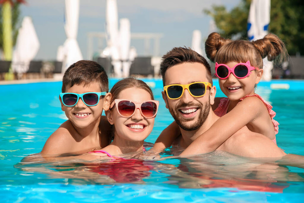 Happy family in swimming pool on sunny day - Fotó, kép