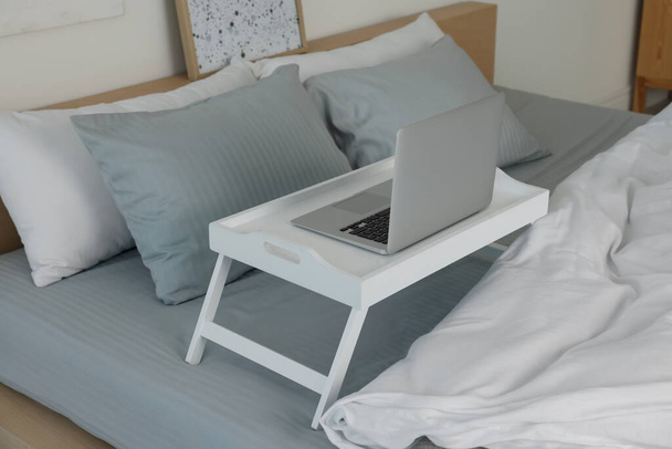 White tray table with laptop on bed indoors - Fotoğraf, Görsel