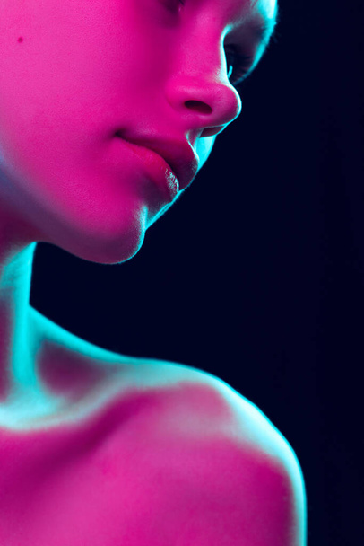 Fantasy. Closeup female lips, cheeks and nose isolated over dark background in neon light. Natural beauty. Concept of natural beauty, cosmetology, skincare, cosmetics, plastic surgery, ad - Foto, Imagen