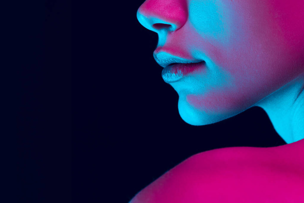Fantasy. Closeup female lips, cheeks and nose isolated over dark background in neon light. Natural beauty. Concept of natural beauty, cosmetology, skincare, cosmetics, plastic surgery, ad - Fotografie, Obrázek