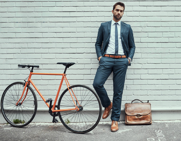 Moving around in style. Portrait of a handsome young businessman standing alongside his bike outdoors - Foto, afbeelding