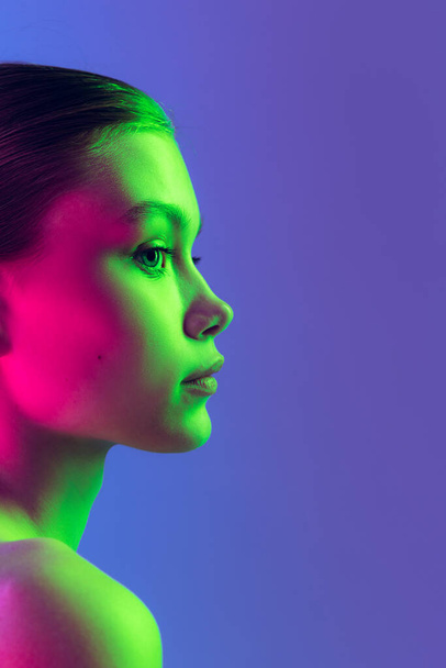 Serious and thoughtful. Attractive young, beautiful girl with well-kept skin isolated on blue background in neon light. Art, fashion, style, facial expression, eco products and health - Foto, Imagem