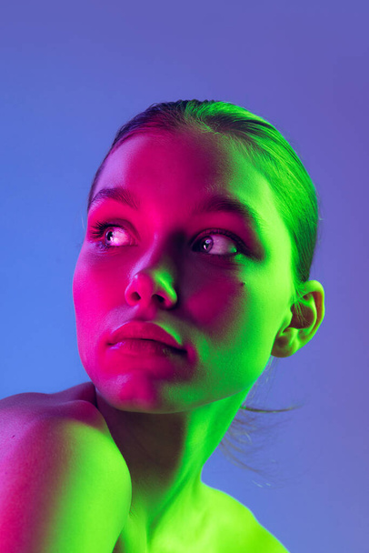 Night life. Young adorable sad girl posing isolated over blue background in neon light. Concept of natural beauty, art, emotions, cosmetics and youth. Flyer for ad. Looks calm - Photo, image