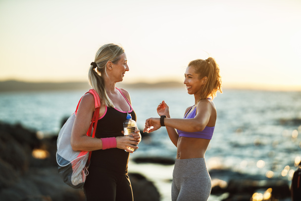 Mother and her adult daughter talking and support each other before training near the sea beach. - Foto, Imagem