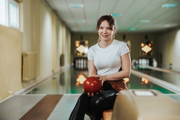 Shot of a cute girl holding bowling ball in the bowling club. Looking at camera - Fotografie, Obrázek