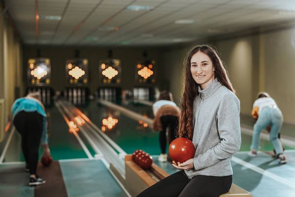 Shot of a cute girl holding bowling ball at the bowling club and looking at camera. - Fotografie, Obrázek