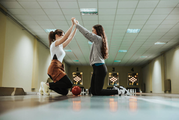Two young girls giving high five at the bowling club. - Fotografie, Obrázek