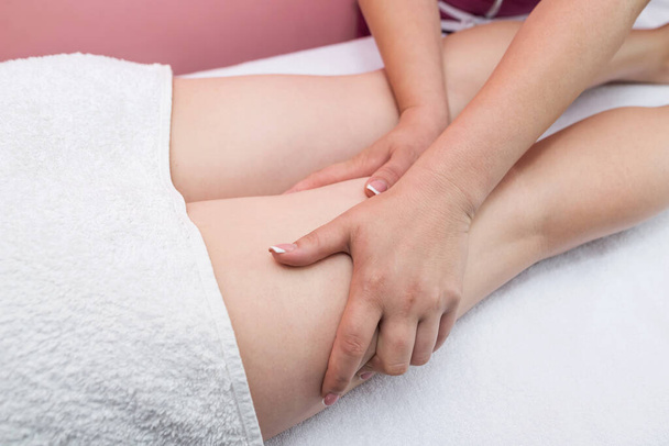 Massage of the legs and buttocks to reduce cellulite and maintain a healthy look.Masseuse makes anti-cellulite massage of legs, hips, thighs and buttocks in a spa salon. Overweight treatment, body sculpture. The concept of cosmetology and massage. - Zdjęcie, obraz