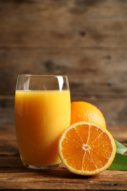 Glass of orange juice and fresh fruits on wooden table - Fotoğraf, Görsel