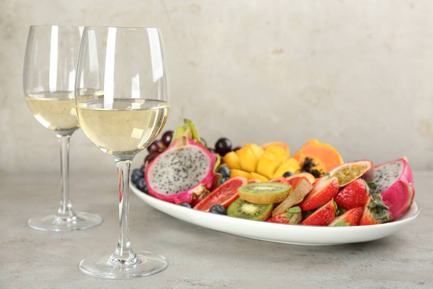 Delicious exotic fruits and wine on grey table - Фото, зображення