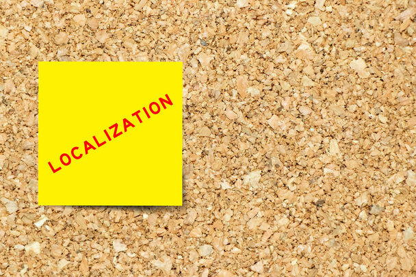 Yellow note paper with word localization on cork board background with copy space - Photo, image