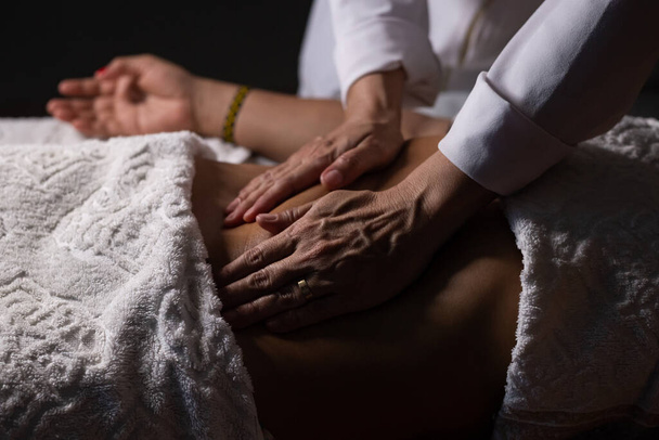 Closeup of massage therapist hands applying therapeutic massage on a patient's belly. - Fotografie, Obrázek