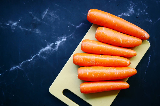fresh carrots on chopping board on table . - Φωτογραφία, εικόνα