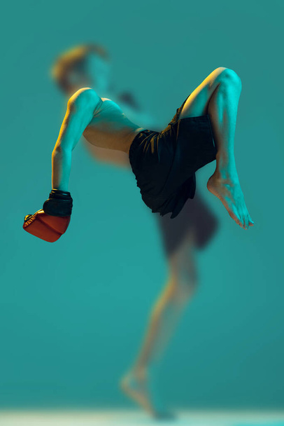 Marital arts. Foggy glass effect. Little boy, beginner fighter of mma sport in action isolated on cyan color background. Beginner fighter of mma in action, motion, sport, challenges. Copy space for ad - Foto, Imagen