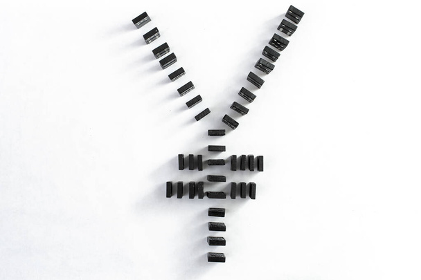 chinese currency symbol  made with black domino tiels,  isolated on white background.  Market volatility concept.  - Photo, Image