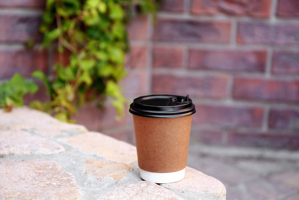 Disposable paper cup with plastic lid on stone parapet outdoors - Foto, immagini