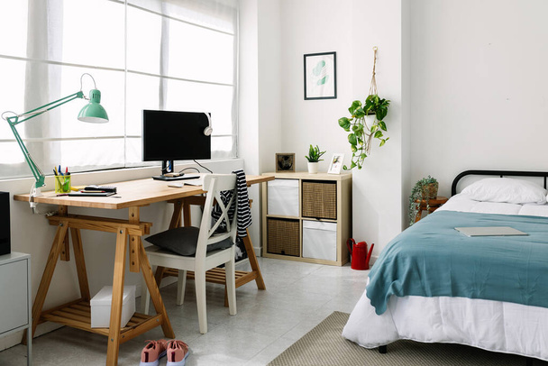 Cozy interior millennial teenage room with bed, laptop and desk - Фото, изображение