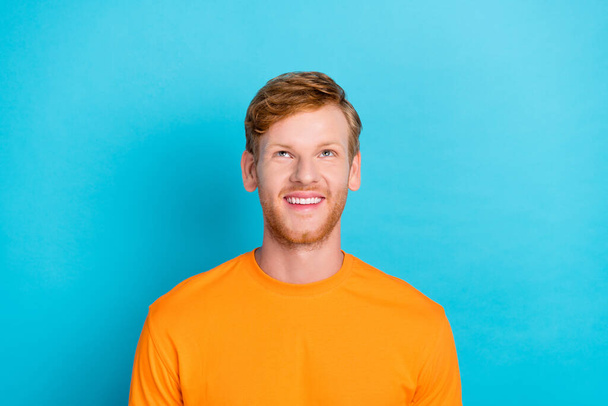 Φωτογραφία του χαρούμενου θετική όμορφος άντρας με κόκκινα μαλλιά ντυμένος πορτοκαλί t-shirt αναζητούν κενό χώρο που απομονώνονται σε τυρκουάζ φόντο χρώμα. - Φωτογραφία, εικόνα
