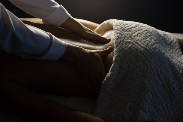 Detail of a massage therapist massaging the back of a patient who is lying on a stretcher. - Photo, Image
