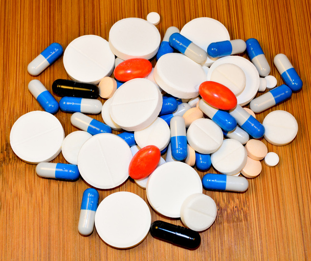 Egy csomó tabletták és kapszulák, fából készült háttér - Fotó, kép