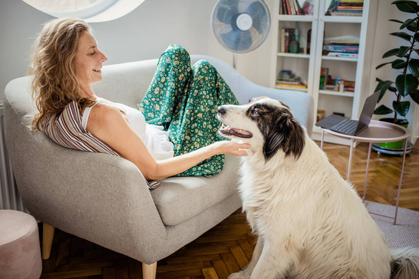 жінка і білий собака розслабляється на дивані
 - Фото, зображення