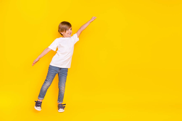Full length body size view of handsome cheerful pre-teen boy struggling copy space isolated over vivid yellow color background. - Photo, Image