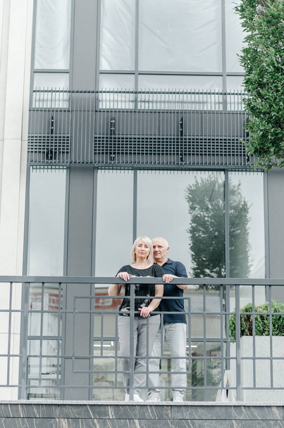 a woman and a man embrace near a glass building - 写真・画像