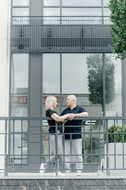 a woman and a man embrace near a glass building - Foto, Imagem
