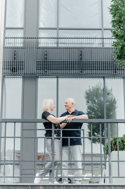 a woman and a man embrace near a glass building - Foto, afbeelding
