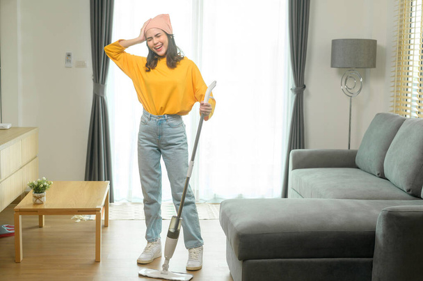 A Young happy woman mopping and vacuum the floor in living room. - Foto, Imagen