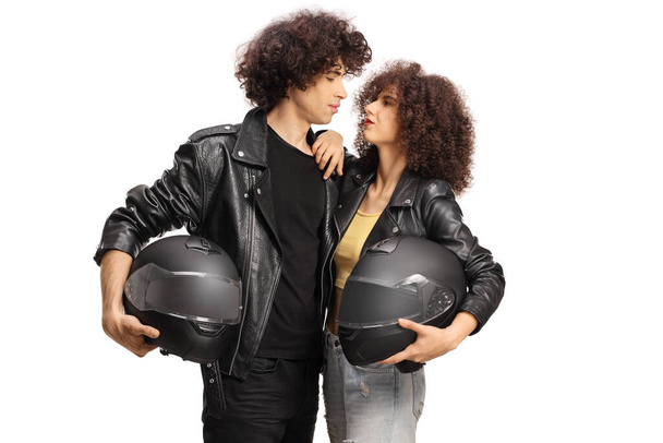 Young couple in leather jackets holding motorbike helmets isolated on white background - Photo, Image