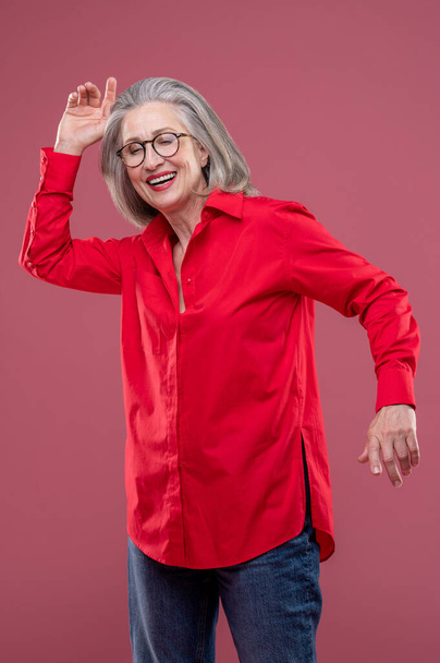 Energized. Woman in red shirt moving and smiling - Фото, изображение