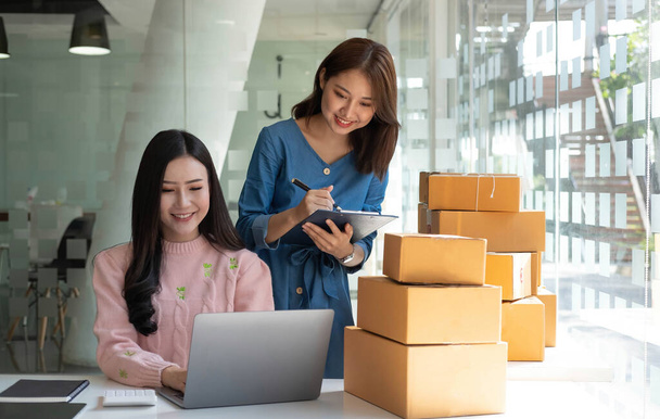 Portrait of Starting small businesses SME owners, two Asian woman check online orders Selling products working with boxs freelance work at home office, sme business online small medium enterpris - Photo, Image