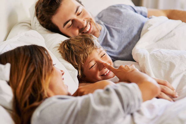 Look who sneaked in here. a cheerful young family relaxing in bed at home during the day - Foto, imagen