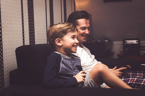 Happy little boy and his father having fun while playing video game together at home.  - Foto, immagini