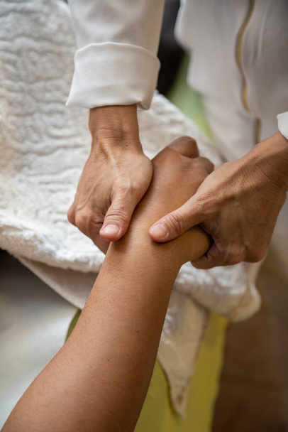 Detail of hands of masseur, who is applying therapeutic massage on the hand of a patient who is lying down. - Foto, imagen
