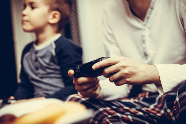 Крупним планом чоловік грає у відеогру зі своїм сином вдома
.  - Фото, зображення