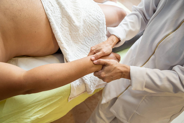 Detail of hands of masseur, who is applying therapeutic massage on the hand of a patient who is lying down. - Photo, Image