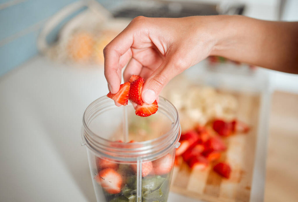 Υγιή, δίαιτα και φρούτα κατά την προετοιμασία ενός smoothie ή ανακινήστε σε ένα μπλέντερ στο σπίτι. Φτιάχνοντας ένα φρέσκο σπιτικό βιολογικό ποτό με φράουλες για καθαρισμό και παροχή ενέργειας για ζωτικότητα και υγεία. - Φωτογραφία, εικόνα