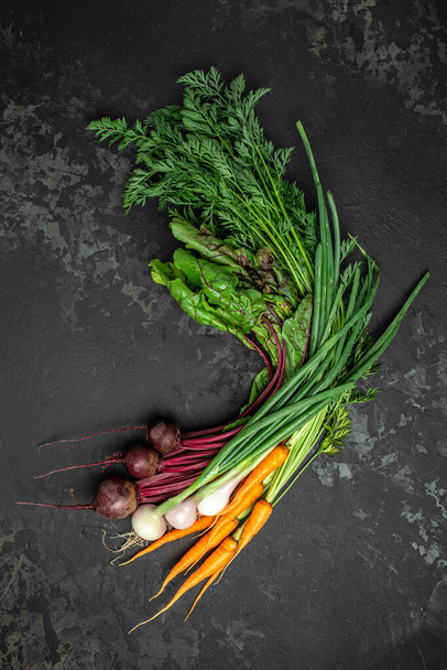 Egy rakás friss bio cékla és sárgarépa zöld levelekkel. hagyma fokhagyma fej, A koncepció a mezőgazdaság és a kertészkedés, növekvő és gondoskodó zöldségek. felülnézet. - Fotó, kép